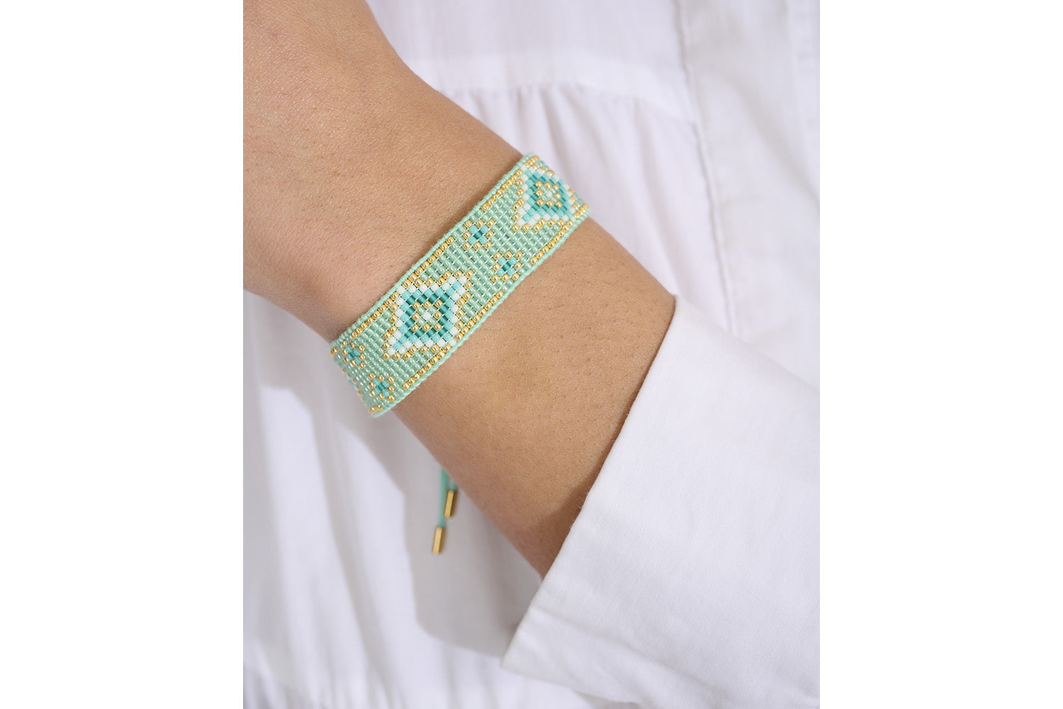 Carys Aqua Gold Friendship Bracelet styled on the wrist, showcasing teal and gold Miyuki beads, perfect for layering with other boho jewellery or wearing solo.