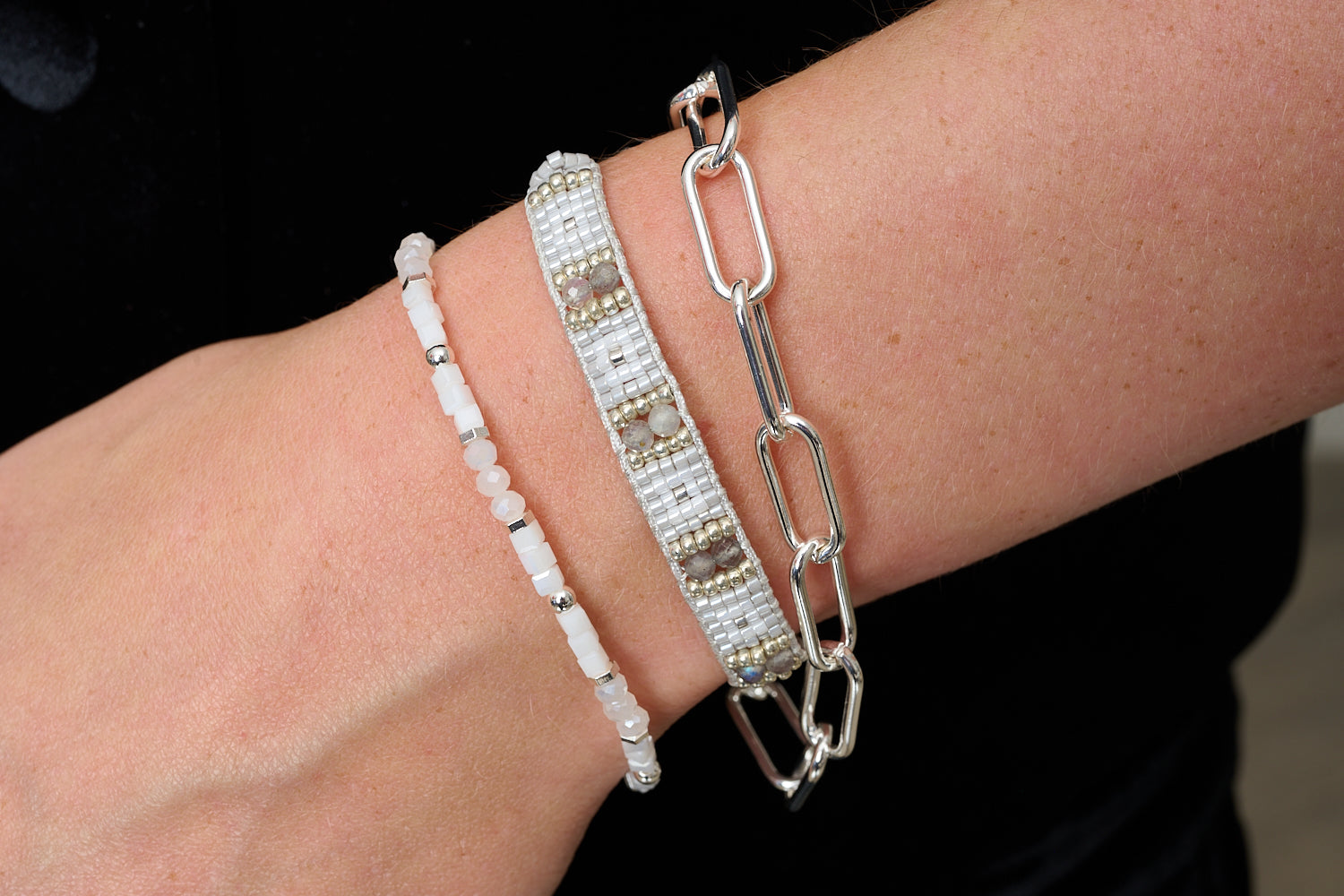 Chico bracelet stack styled with monochrome outfit, soft greys, white beads and modern silver chain.