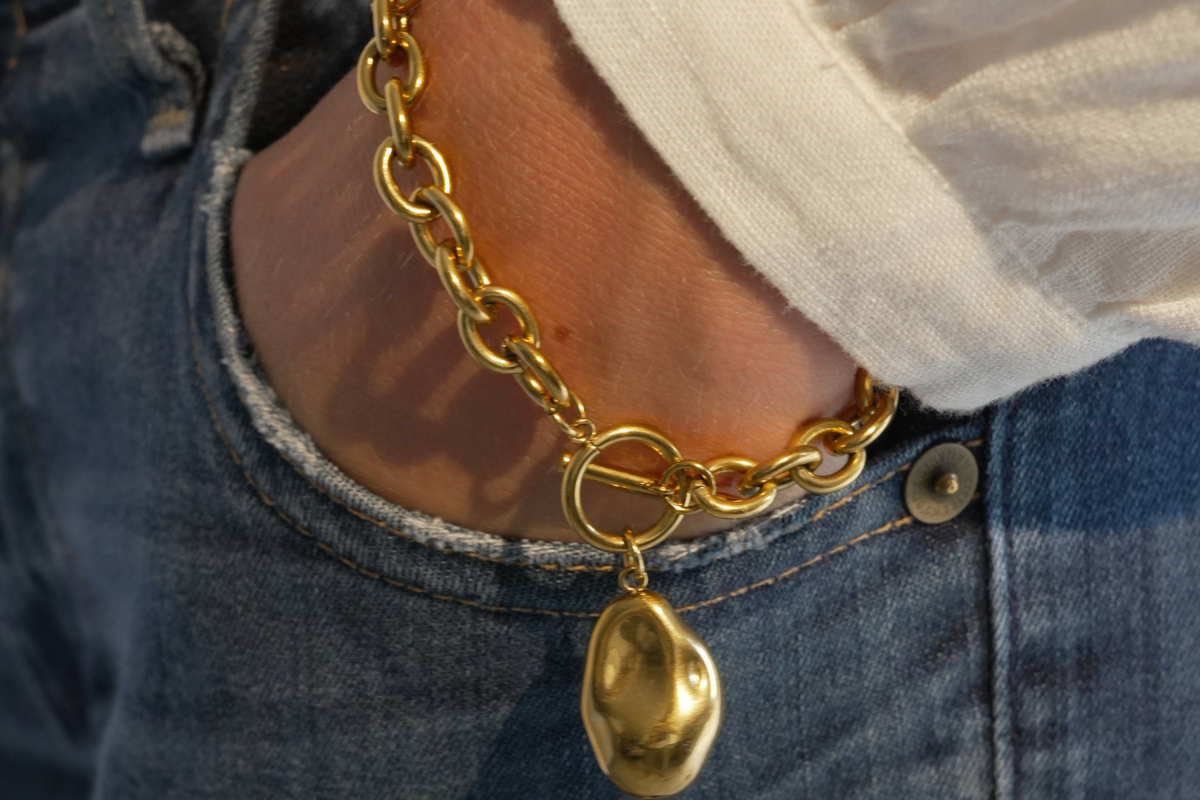 Rasa Gold Nugget Charm T-Bar Chain Bracelet worn as a statement piece, featuring chunky gold links, a sculptural nugget charm and T-bar fastening.