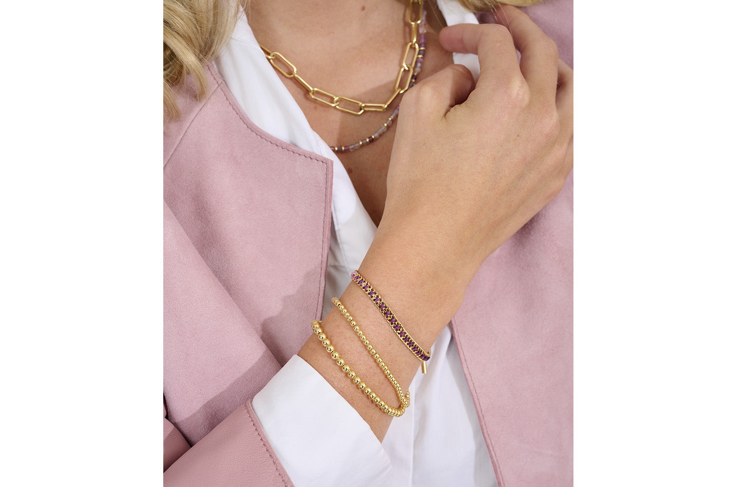 Jeju Purple & Gold Bracelet Stack styled on the model with soft tailoring and layered gold necklaces and bracelets for a stunning feminine look.