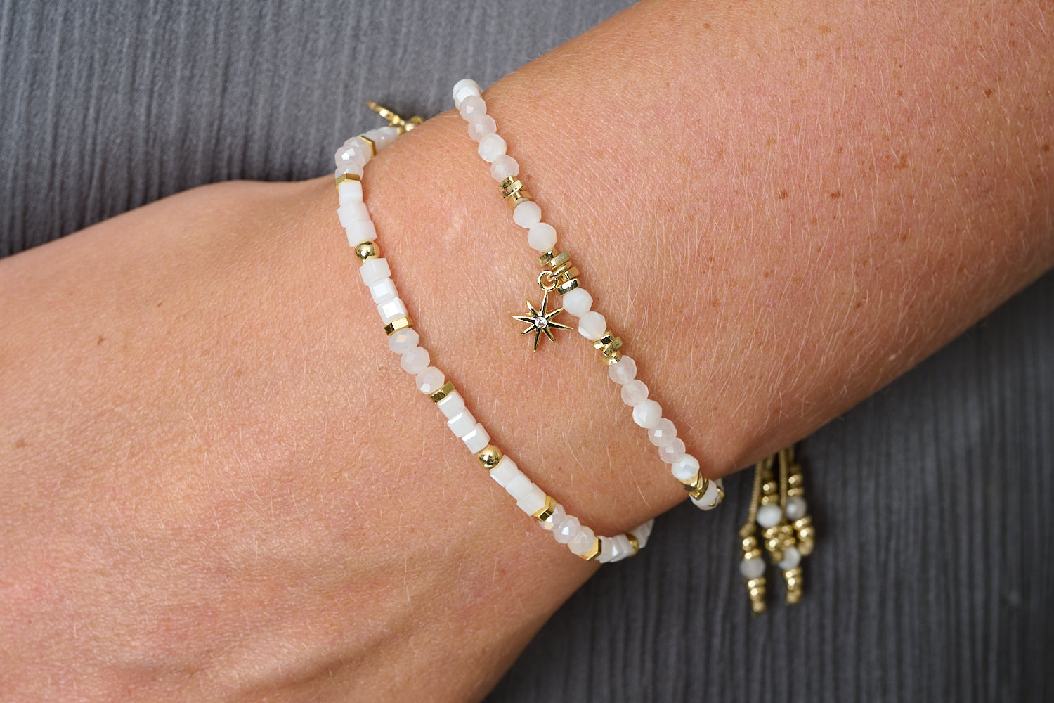 Mogo rainbow moonstone and gold stacking bracelets styled on wrist, soft white gemstones glowing with golden light.