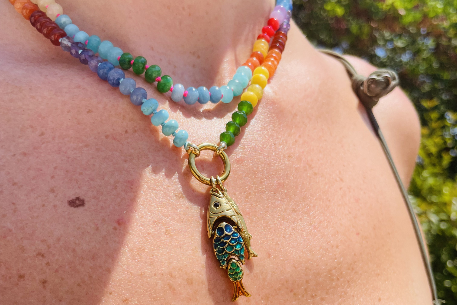 Model wearing the Amala Rainbow Bead Gold Fish Cluster Charm Carrier Necklace with a colourful gemstone bead carrier and a rainbow enamel fish cluster in waterproof 14k gold PVD.