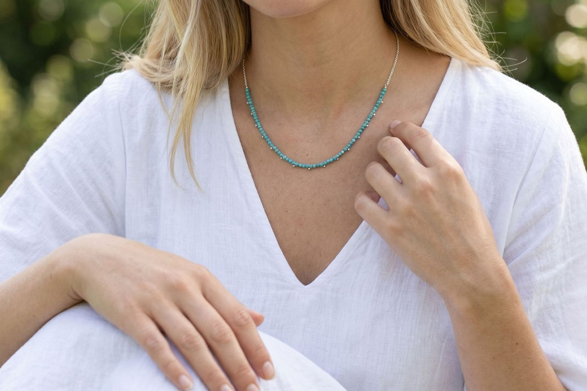Salus Turquoise Howlite Silver Necklace styled around the neckline, showcasing turquoise howlite gemstones and waterproof silver PVD details designed for everyday wear and effortless layering.