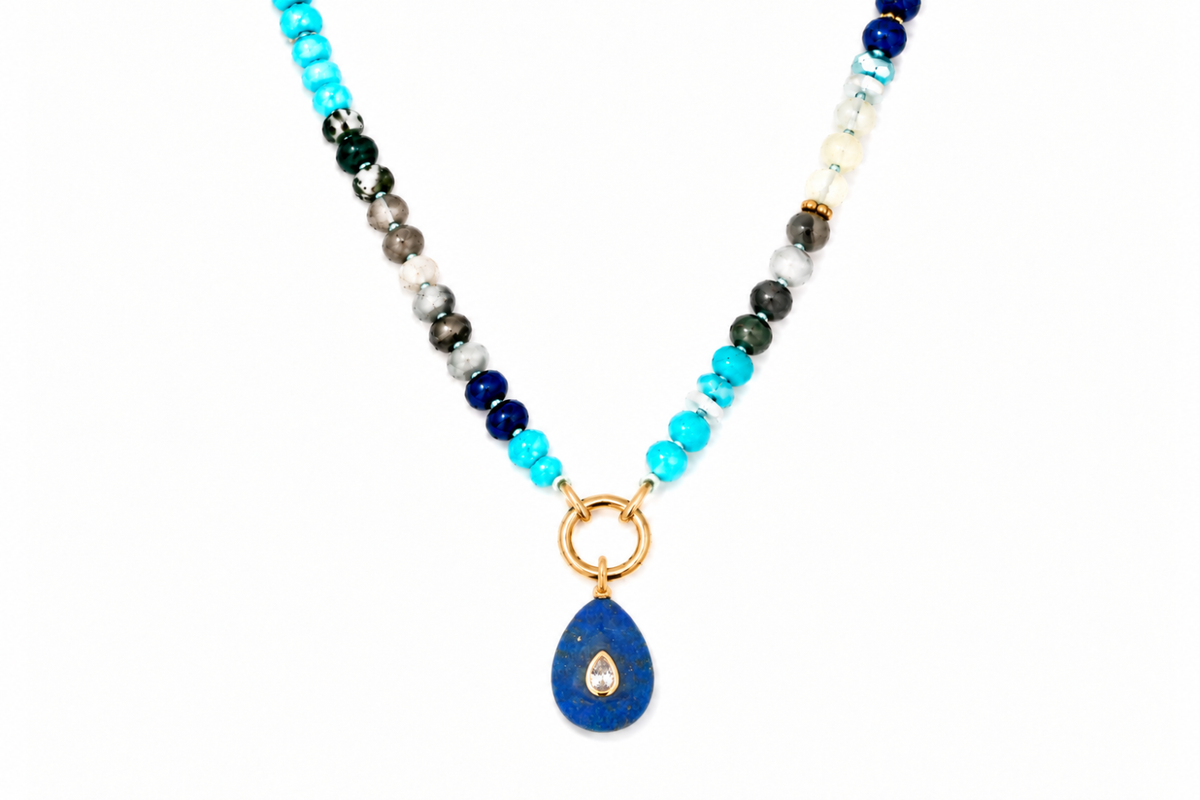 Amala Blue Mix gold charm carrier necklace finished with a Fleur lapis lazuli teardrop pendant, a waterproof Boho Betty gemstone necklace.