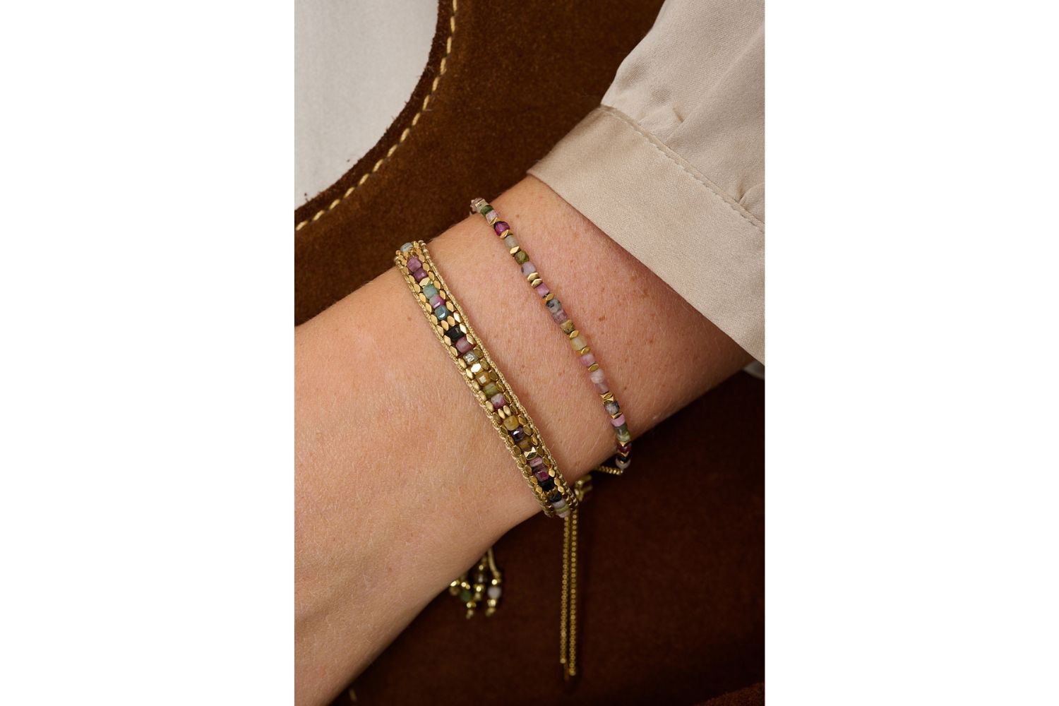 Anastasia Gold & Tourmaline Beaded Bracelet styled on the wrist, showcasing natural tourmaline gemstones, a taupe woven cord, and delicate gold-plated accents—perfect for stacking or wearing solo.