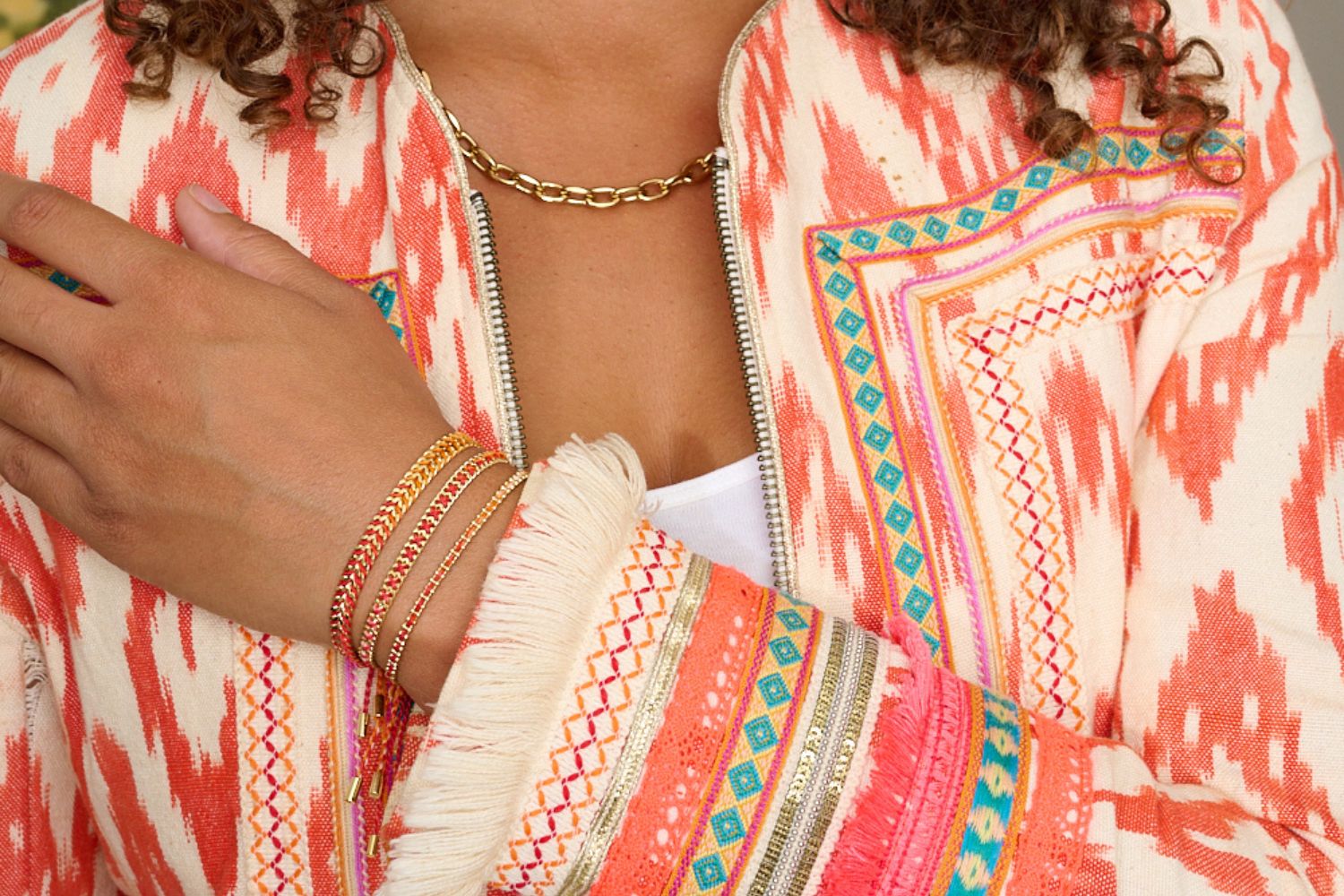 Banda Sunset Gold Stacking Bracelets styled on the wrist, vibrant sunset ombré threads and gold chain layers for a warm, glowing summer look.