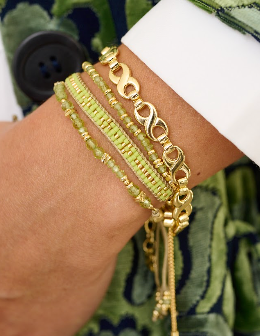 Mana Peridot Gold Bracelet Stack styled on the wrist, showcasing bright green peridot beads and shimmering gold accents for a bohemian chic look.