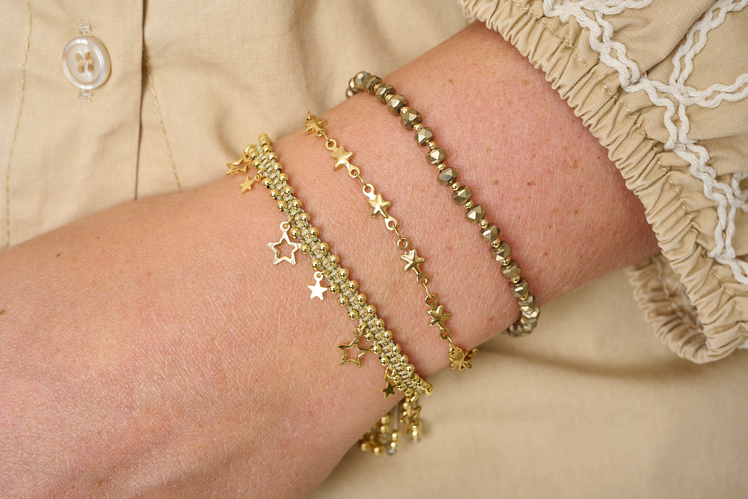 Pomona stacking bracelets styled in neutral tones, soft taupe and gold layers with star accents for relaxed-luxe glow.