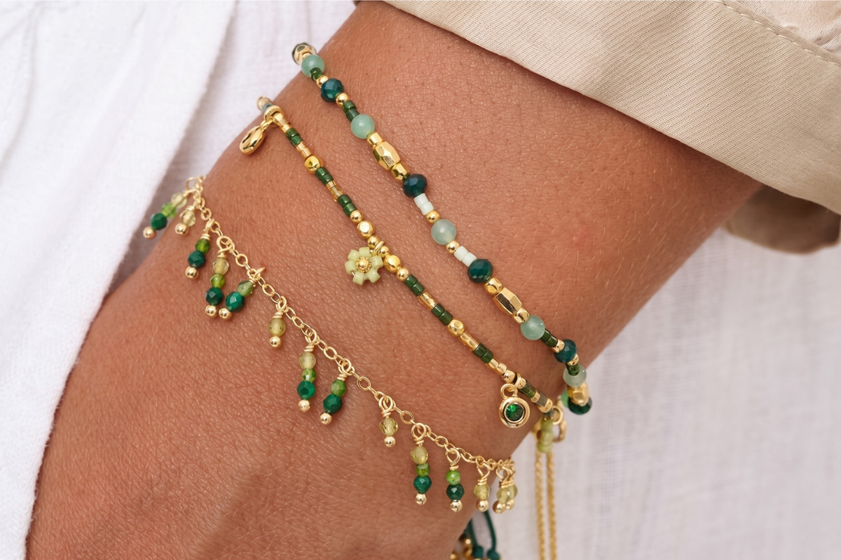 Silba Malachite and Gold Bracelet Stack styled on the wrist, showcasing layered green gemstone beads, gold chain details and nature-inspired woven textures.
