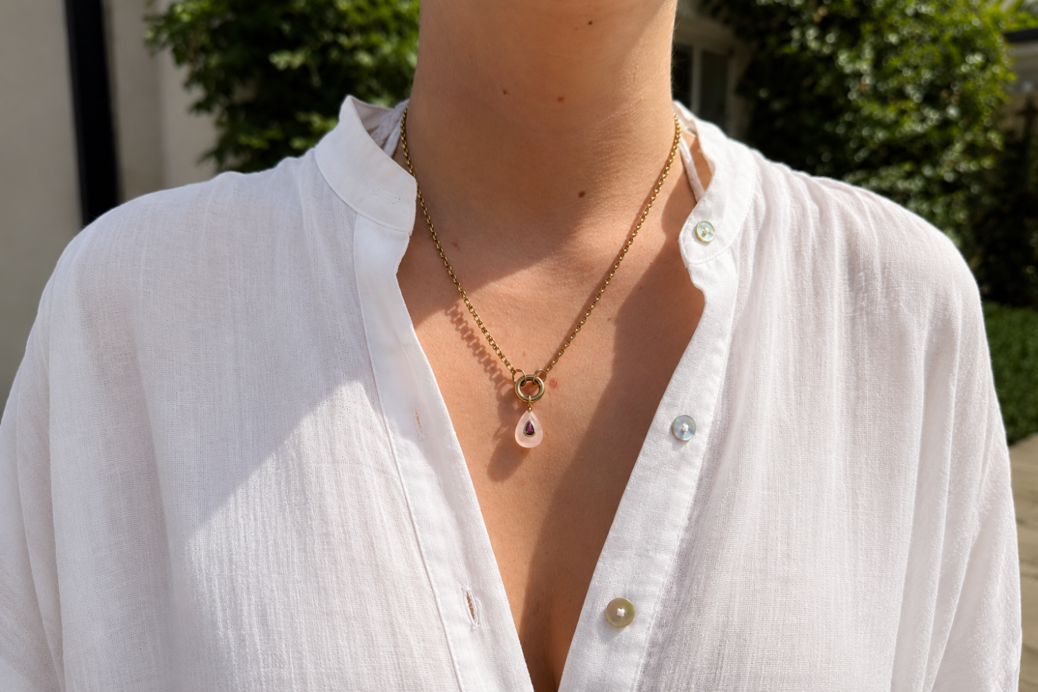 Thalia Short Rose Quartz Teardrop Pendant Necklace worn layered on the neckline with a rose quartz pendant and waterproof 14k gold PVD chain.